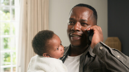 Father Holding Baby While Talking on a Smartphone in a Bright Modern Home