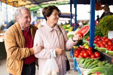  elderly man and woman buy tomatoes at an open market