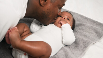 Father Affectionately Interacting With His Infant Child While Lying on a Comfortable Surface in a Cozy Home Setting