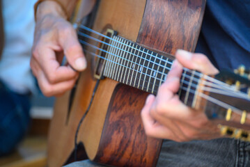 Obraz premium Close-up of hands strumming the strings of a wooden acoustic guitar. Strumming strings.
