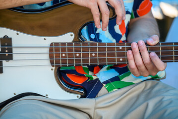 Hands and fingers on the strings of a bass guitar. Plucking strings.