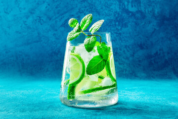 Lime lemonade, or limeade, in a glass with lime, mint, and ice. Fresh summer Mojito mocktail or...