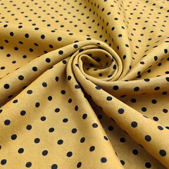 Close up of gold fabric with black polka dots in a swirling pattern