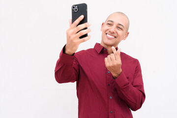 Portrait of man using mobile phone taking selfie against white background