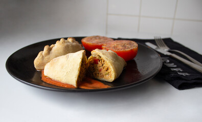 Delicious Argentine empanadas accompanied by chopped tomatoes with olive oil and oregano. 