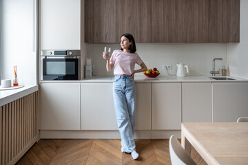 Woman drinking cool water in kitchen for start good day. Female holding glass of water for...