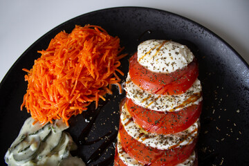 Vegetarian dish with a delicious Italian caprese salad, with olive oil and balsamic vinegar; with grated carrot salad and cucumber salad with cream vinaigrette.