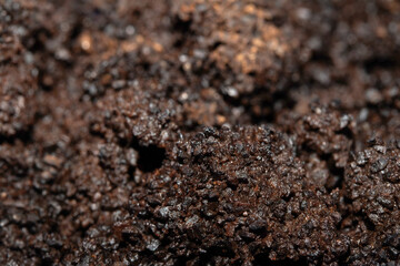 Close up of wet coffee grinds that looks like soil or mud background