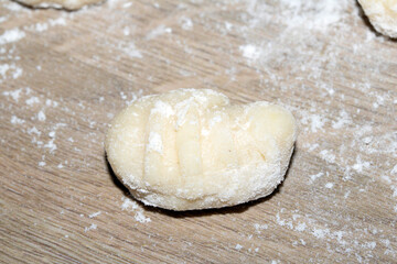 Close up of gnocchi pasta beinng made raw on wooden background covered in flour