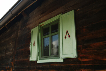 Close-up of a green wooden window shutter with cut-out motifs on a rustic house in Drvengrad,...
