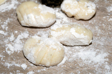 Close up of gnocchi pasta beinng made raw on wooden background covered in flour