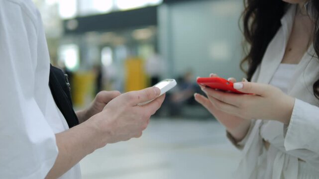 Two women are holding cell phones and one of them is red. The other woman is wearing a white shirt