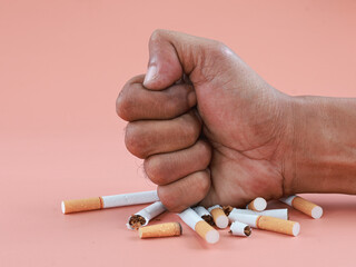 Male hand smashed pile of cigarette on isolated background. Stop smoking concept.
