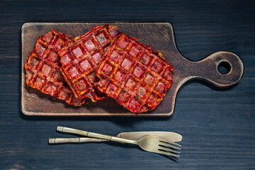 Vegetarian beetroot and zucchini waffles with herbs on wooden table, closeup, top view. Tasty...