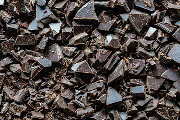 Pile broken dark chocolate bar on background, closeup, top view,. Sweet food