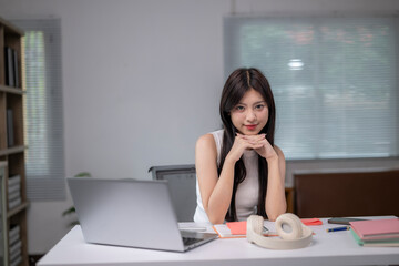 Obraz premium A woman is sitting at a desk with a laptop and a pair of headphones
