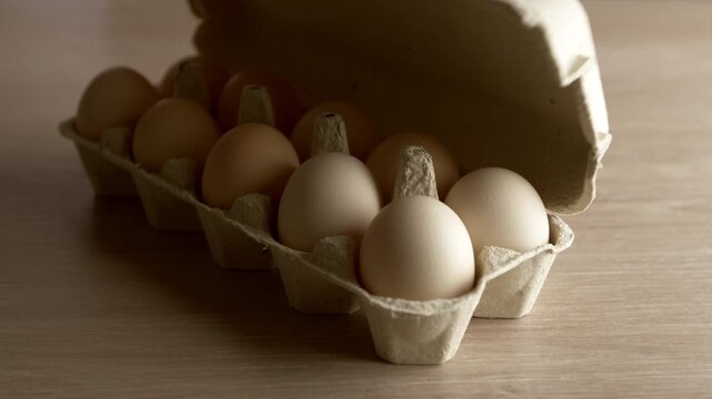 Raw chicken eggs in a tray are opened by hand.