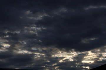 Dramatic timelapse of dark storm clouds rolling across a turbulent blue sky at sunset