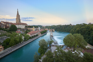Naklejka premium View of the Aare River with buildings and a historic tower in Bern during twilight hours