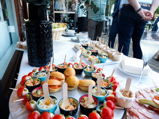 Buffet apéritif en extérieur avec mini-burgers, verrines, brochettes tomates-mozzarella et amuse-bouches variés, présentation élégante pour réception festive