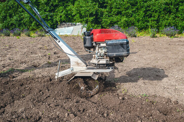 Manual gasoline cultivator plows soil. Close-up of  cultivator motor. Agriculture concept.