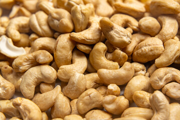 Many cashew nuts - close-up. Numerous cashew nuts lie on a white background, close together. The curved shapes almost completely fill the image.