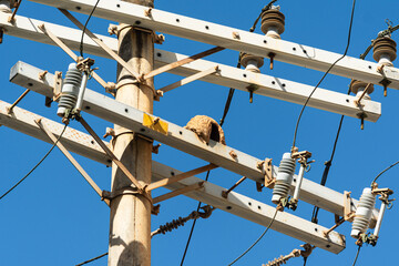 The top of a power pole with a tangle of electrical, internet, and telephone wires and cables....