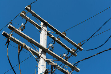The top of a power pole with a tangle of electrical, internet, and telephone wires and cables....
