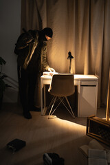 Burglar or intruder with flashlight. Illegally breaking. Male robber wearing black balaclava steals...
