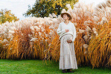 Pregnant woman in nature at autumn. Healthy and happy pregnancy of beautiful woman enjoying moment.