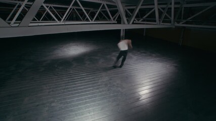 High angle view fast motion of young man dancing emotional contemporary solo in dark warehouse space