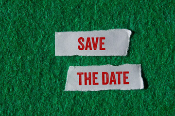 Save the date message written on ripped torn paper pieces on green background. Conceptual save the...