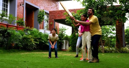 Indian family playing cricket batting in home garden, spending quality fun time together playing outdoor sports, cheerful Asian parents and children enjoying backyard activity bonding on sunny day - Powered by Adobe