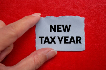 New tax year message written on ripped torn grey paper piece on red background. Conceptual new tax...