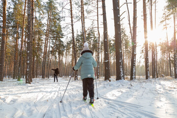 Dad and daughter skiing in the winter forest