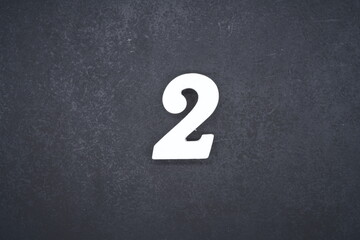 The numbers are made of white painted wood and placed on a black plastic background.