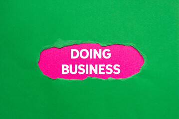 Doing business message written on ripped torn green paper on pink background. Conceptual doing business symbol. Copy space.