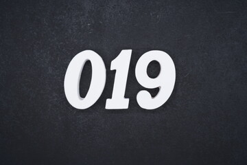 The numbers are made of white painted wood and placed on a black plastic background.