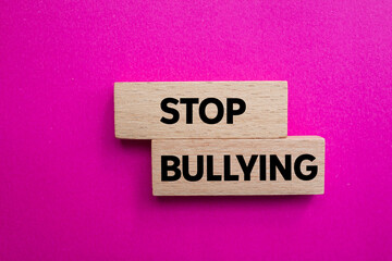 Stop bullying message written on wooden blocks on pink background. Conceptual stop bullying symbol. Copy space.