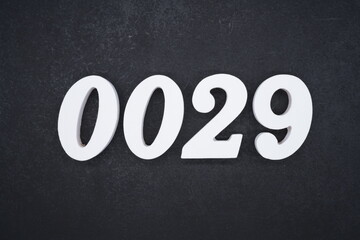 The numbers are made of white painted wood and placed on a black plastic background.