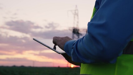 technology concept with high voltage power lines. electrical engineer helmet digital tablet sunset. power engineer power plant high voltage voltage energy. concept electrical engineer working sunset.
