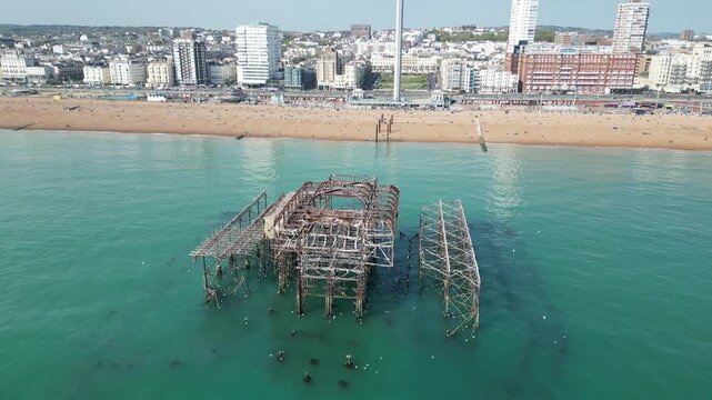 Aerial drone footage flying low over the sea toward and above the skeletal remains of Brighton&rsquo;s West Pier, destroyed by fire in 2003 and now a haunting coastal landmark.