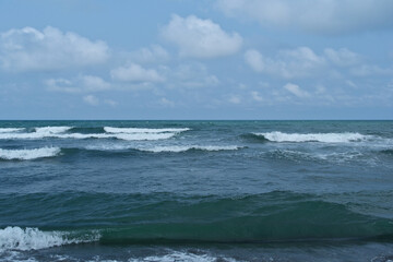 Seascape with waves on the Black Sea coast in Georgia. Waves on the seashore. Blue sky with white clouds.