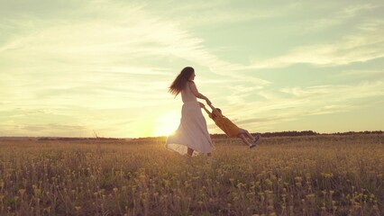 Mother circles her little kid daughter sunset sky. concept happy family park. girl daughter dreams...