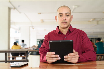 Man using digital tablet computer device at outdoor cafe restaurant table in urban academic setting