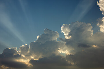 Bright sunbeams shining from behind a cloud in a blue sky. Concept of hope, faith, and spirituality