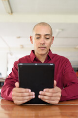 Man using digital tablet computer device at outdoor cafe restaurant table in urban academic setting