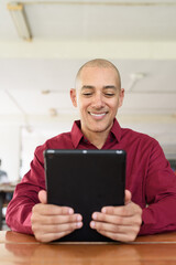 Man using digital tablet computer device at outdoor cafe restaurant table in urban academic setting