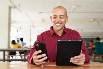 Man using digital tablet computer device at outdoor cafe restaurant table in urban academic setting