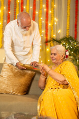 Indian happy senior man giving gold bangles gift to his beautiful wife on the occasion on Diwali...
